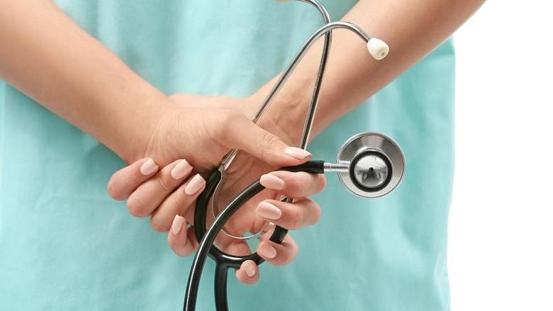 a nurse holding a stethoscope behind her back